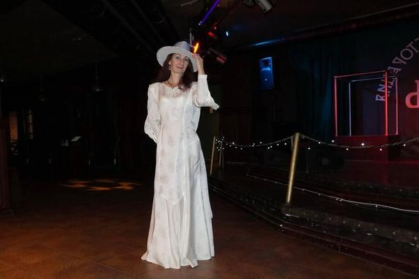 Em vestido de noiva e chapéu branco no palco