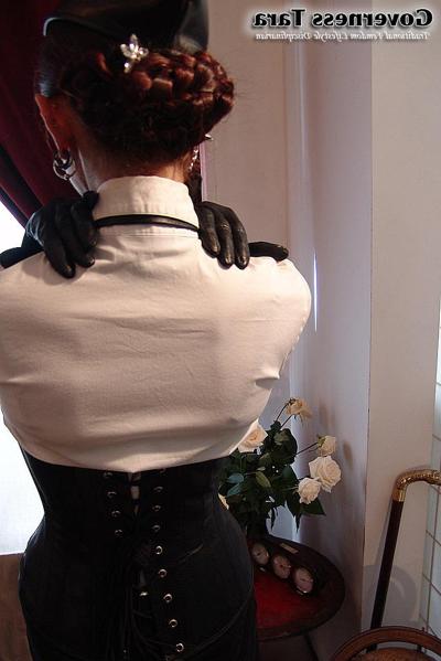 20P Twisted corsetted domina poses in spike heel leather boots