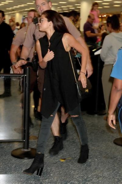 16P Selena Gomez braless showing big cleavage in a black top and jeans at the airpor