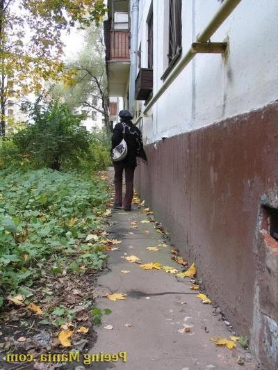 15P Stylishly dressed pretty woman does a leak behind a building in autumn